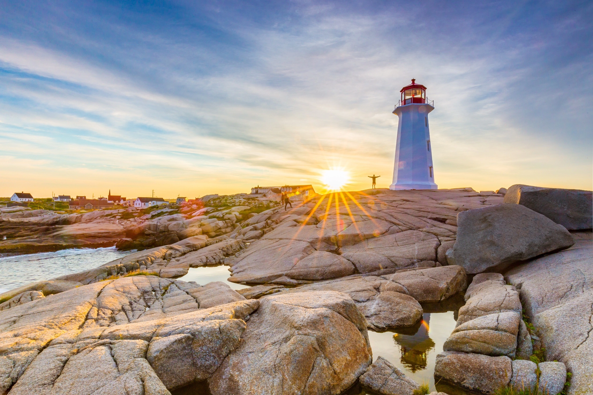 Peggy's Cove lighthouse on rocky coastline with dramatic clouds